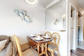 A dining area with a wooden table, four chairs, and a white ceiling light. - Victorian 7103 - Beachfront, Pools & Hot Tubs (Galveston)