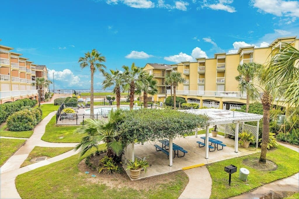 A hotel courtyard with a pool, palm trees, and outdoor seating.