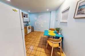 Una cocina compacta con suelo de baldosas, una mesa de comedor con sillas y un mural en la pared con una tortuga.