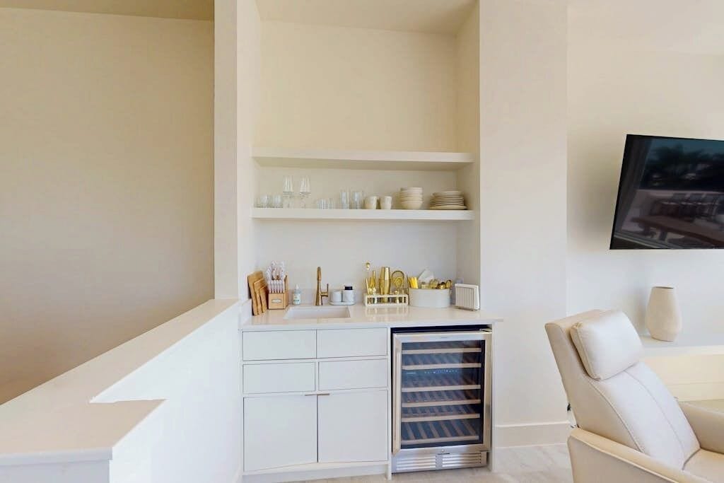 A modern kitchen with white cabinetry, a built-in oven, and a countertop with various kitchen items.