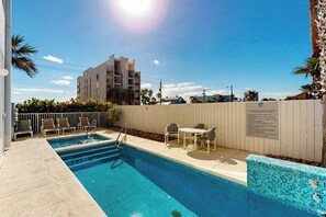 A swimming pool with a sunshade, lounge chairs, and a small table. - Lantana Cove #203 - Gulf Views, Across from Beach (South Padre Island)