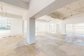 An empty interior space with concrete pillars, large windows, and a tiled floor. - Lantana Cove #203 - Gulf Views, Across from Beach (South Padre Island)
