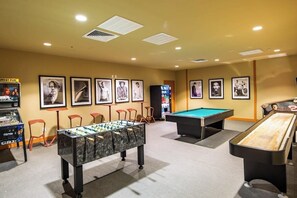 A room with a foosball table, pool table, and a bar area with stools. - Sapphire Condominiums #408 (South Padre Island)