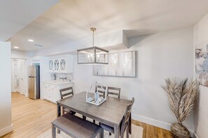 Eine moderne Küche mit weißen Schränken, einem Edelstahlkühlschrank und einem Essbereich mit Holztisch und -stühlen.