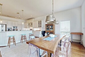 A modern kitchen with white cabinetry, a wooden island, and bar stools. - The Beach Escape - Beachfront Home, Sleeps 16 (Galveston)