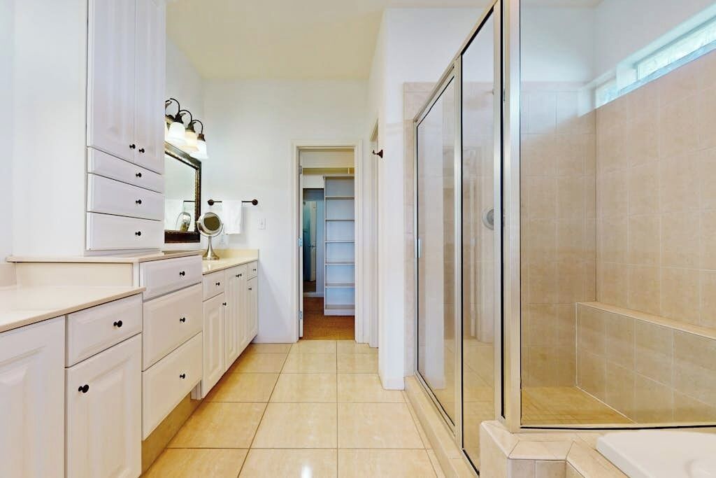 A modern bathroom with a shower, a vanity with drawers, and a mirror.