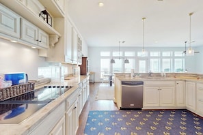 A modern kitchen with white cabinetry, a central island, and pendant lighting. - The Beach Escape - Beachfront Home, Sleeps 16 (Galveston)