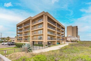 Hotel amb diversos pisos, balcons, zona d'aparcament i vistes a la platja.