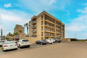 A multi-story hotel with a parking lot in front. - Seagull Condominiums #301 (South Padre Island)