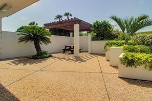 An outdoor patio area with a pergola, a picnic table, and potted plants. - Wandless Waves - Pool & Hot Tub, Steps to Sand (Galveston)