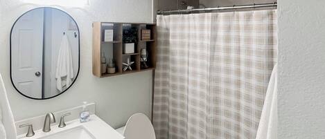 A bathroom with a white sink, a mirror, a toilet, and a shower curtain.