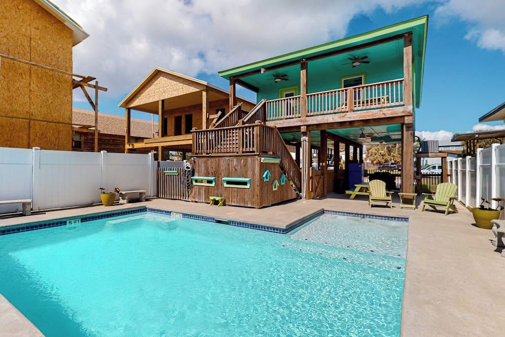 A pool area with a wooden deck, a covered upper level, and outdoor seating.