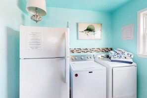 A compact kitchen with a refrigerator, stove, and two stacked washers. - Down By The Sea - Private Pool, Downtown Port A (Port Aransas)