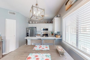A kitchen with white cabinets, a stainless steel refrigerator, and a hanging light fixture. - Leeward Isles 305 - Pool, Near the Beach, Dogs OK (Corpus Christi)