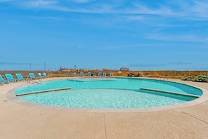 Ein Swimmingpool mit Liegestühlen und blauem Himmel.