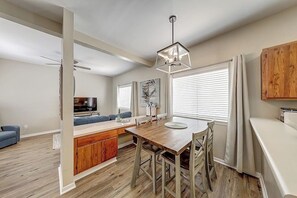 A modern kitchen with a wooden island, a dining table with chairs, and a pendant light. - Leeward Isles 207 - Pool, Walk to the Water (Corpus Christi)