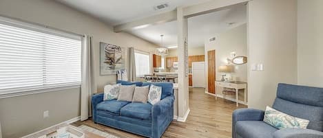 A spacious living room with a blue sofa, a coffee table, and a ceiling fan.