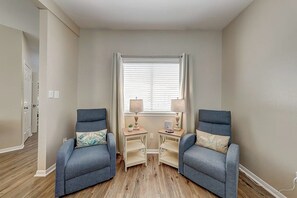A room with two armchairs, a small table, and a window with blinds. - Leeward Isles 207 - Pool, Walk to the Water (Corpus Christi)