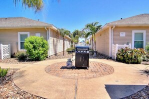 A residential area with two houses, a barbecue grill, and a paved driveway. - Palm Bay 307 - Heated Pool, Walk to the Beach (Corpus Christi)