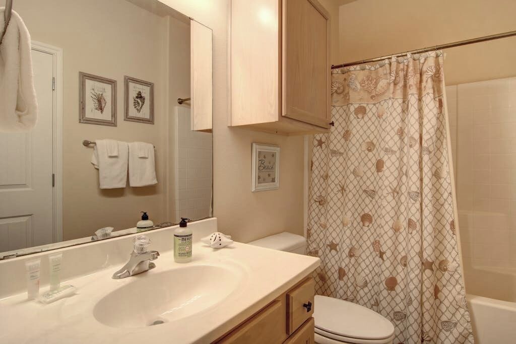 A bathroom with a sink, toilet, and shower curtain.