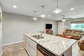A spacious kitchen with a granite countertop, stainless steel sink, and overhead lighting. - The Moor The Merrier (Port Aransas)