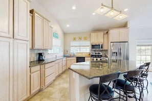 A modern kitchen with granite countertops, stainless steel appliances, and a central island with bar stools. - Fulton Bliss - Boat Parking, Porch & Dogs OK (Rockport)