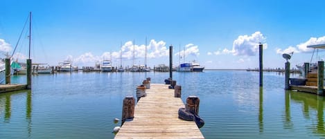Un muelle de madera que conduce a un puerto deportivo con barcos amarrados.