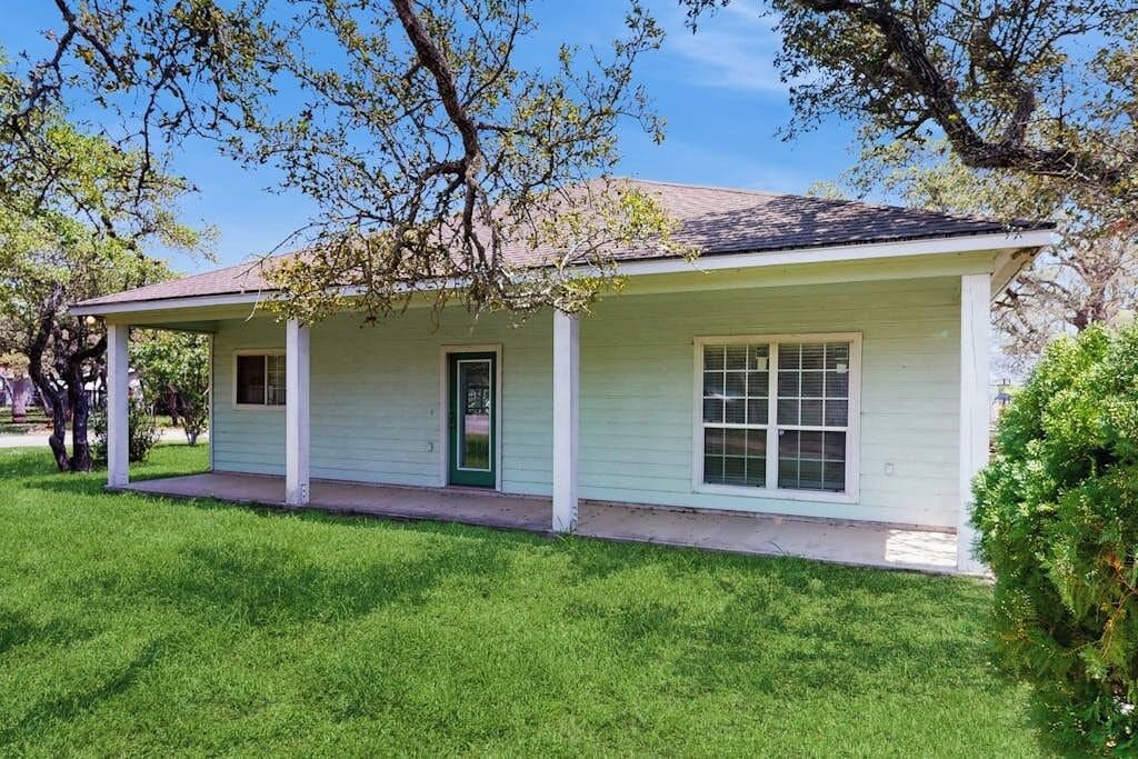 A single-story house with a front porch, a green door, and a window with a grid pattern.