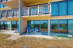 A modern building with a balcony, large windows, and outdoor seating. - Island House #105 - Heated Pool & Outdoor Patio (Corpus Christi)