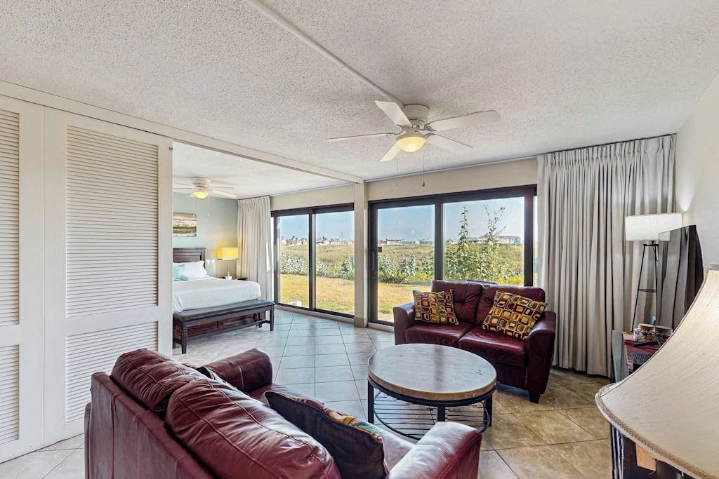 A hotel room with a bed, a sofa, a coffee table, and a balcony with a view.