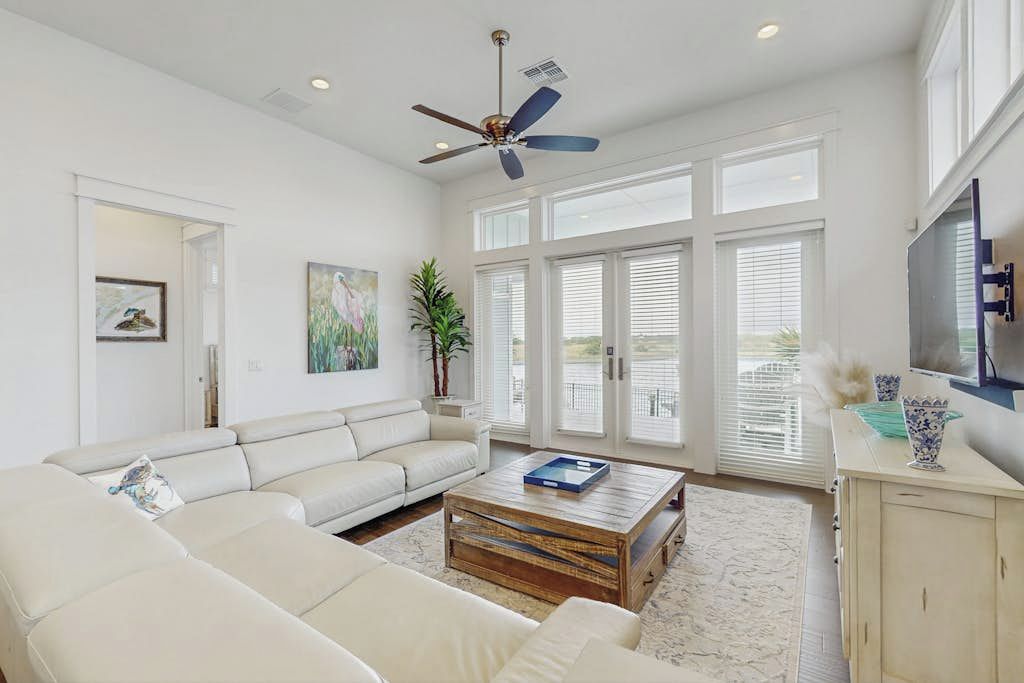 A spacious living room with a white sofa, a coffee table, and a ceiling fan.