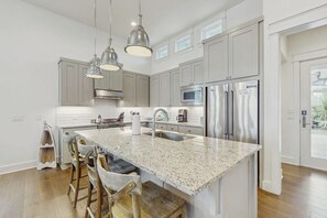 A modern kitchen with granite countertops, stainless steel appliances, and pendant lighting. - Reserve Lane Retreat | Reserve at St Charles Bay (Rockport)