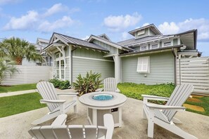 A house with a patio area featuring Adirondack chairs and a fire pit. - Reserve Lane Retreat | Reserve at St Charles Bay (Rockport)