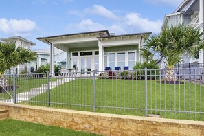 Une propriété résidentielle dotée d’un patio couvert, d’une pelouse bien entretenue et d’un mur de soutènement en pierre.
