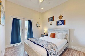 A bedroom with a bed, a nightstand, a wall clock, and a window with curtains. - Coral Reef Gataway - Pool, Playground & Bay Views (Rockport)