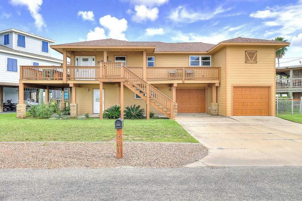 A two-story residential house with a front porch, a garage, and a well-maintained lawn.