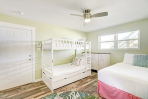 Een kamer met stapelbedden, een bureau, een stoel, een bed en een raam.