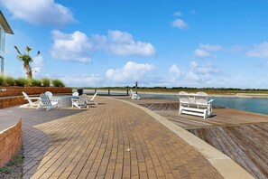 A wooden deck with lounge chairs and a bench overlooking a body of water. - Reserve at St Charles Bay Reserve Villa 601 (Rockport)