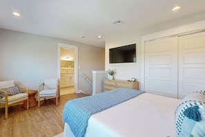 A bedroom with a bed, a chair, a dresser, a television, and a closet. - Reserve at St Charles Bay Reserve Villa 601 (Rockport)