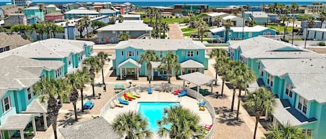 A resort with a central pool surrounded by palm trees and guest rooms.