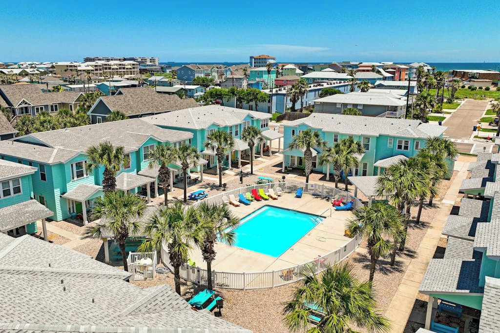 A residential area with a swimming pool surrounded by houses and palm trees.