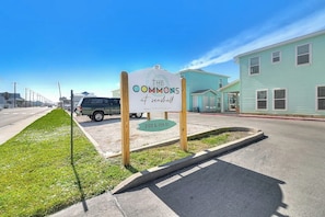 Un panneau de signalisation indiquant « The Commons at Seaside », avec une route dégagée et des bâtiments en arrière-plan.