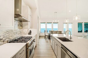 A modern kitchen with a large island, stainless steel appliances, and a view of the ocean. - Casa Bahia San Carlos (Rockport)