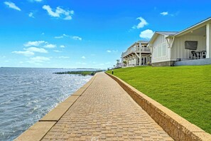 Een waterkantpad dat leidt naar een gebouw met een overdekte veranda en een gazon.