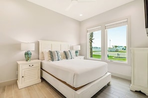 Een slaapkamer met een groot bed, nachtkastjes, een raam met uitzicht en een plafondventilator.