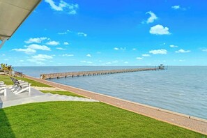 A pier extending into calm water, a grassy area with a pathway, and a clear sky. - Casa Bahia San Carlos (Rockport)