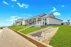 Une propriété située en bord de mer, dotée d’un patio couvert, d’une piscine et d’une pelouse bien entretenue.