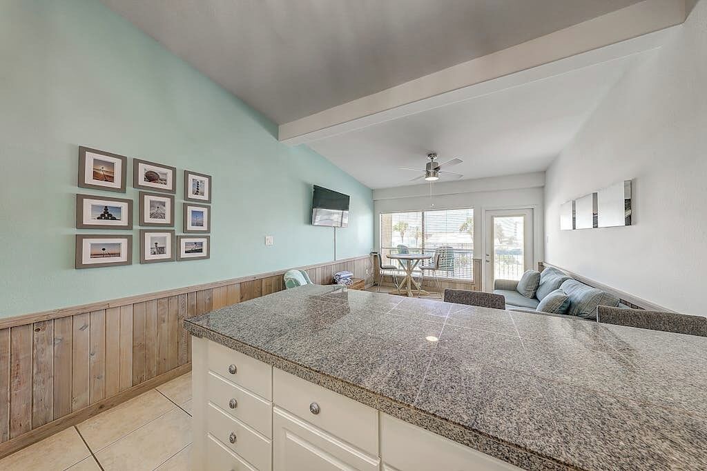 A kitchen with a granite countertop, wooden paneling, and a dining area with a table and chairs.