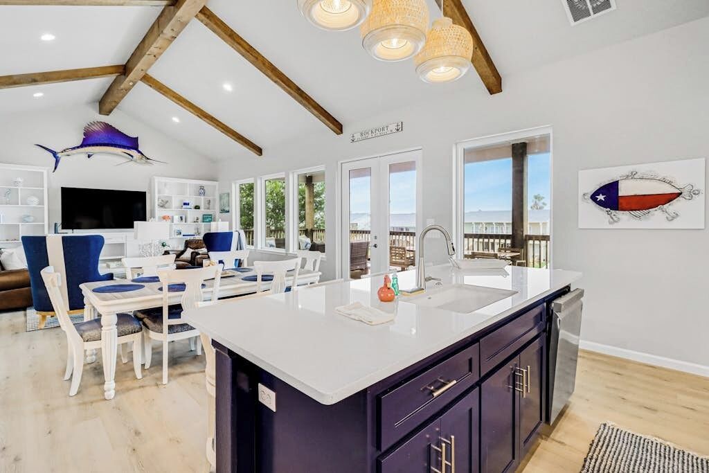 A modern kitchen with a central island, white cabinetry, and a view to the outside.