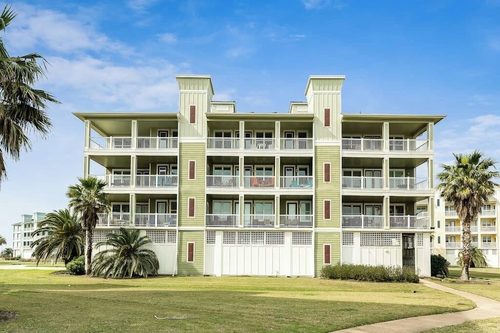 A multi-story hotel with balconies, a flat roof, and a well-maintained lawn.